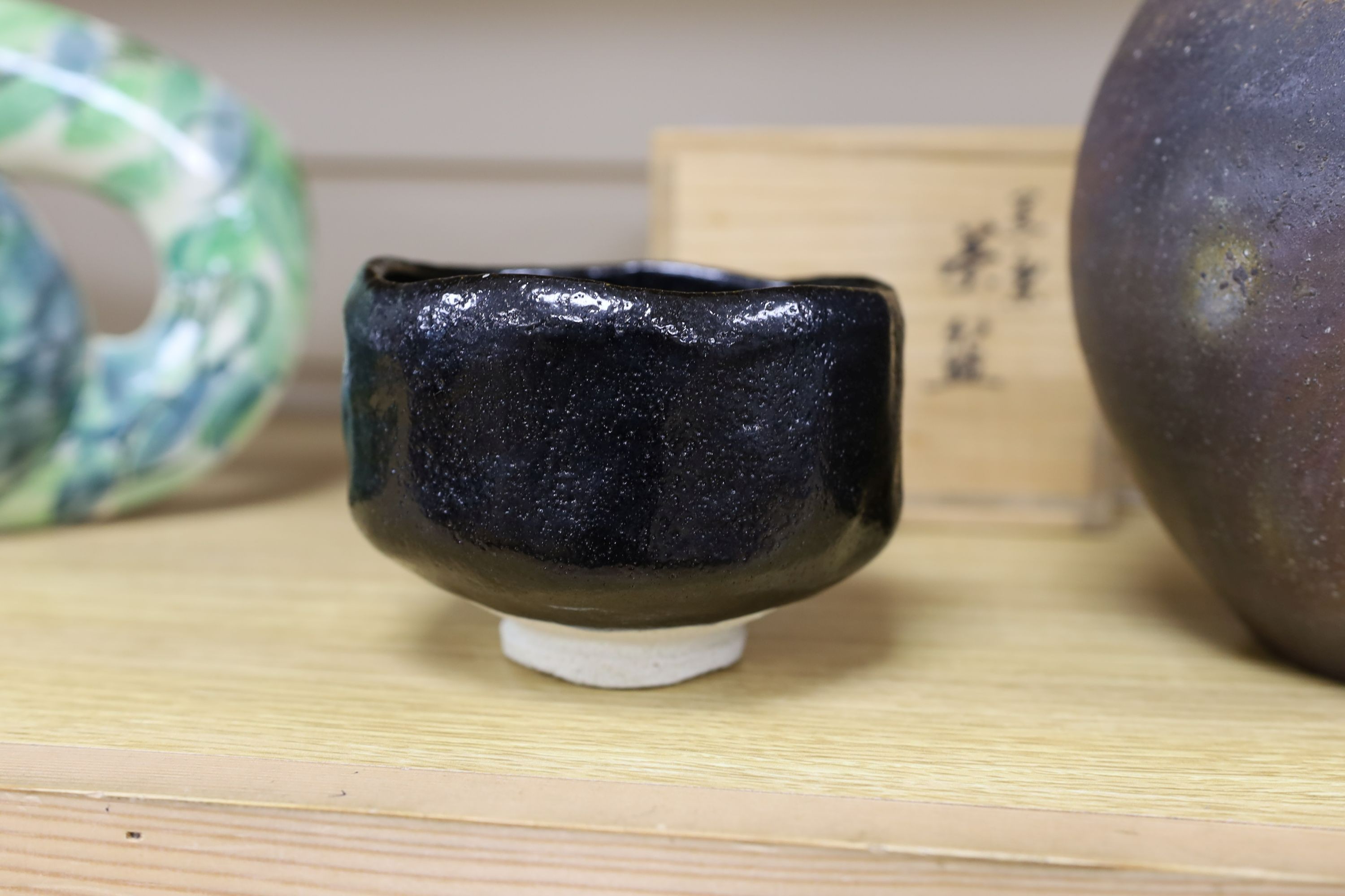 Japanese studio pottery: a boxed black glaze stoneware unomi tea bowl, with impressed mark, together with a ovoid vase, marked, 21cm tall